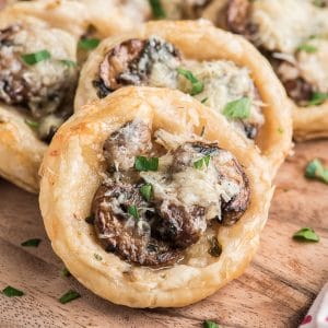 Mushroom puff pastry appetizers on a wooden board.