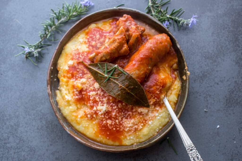 Polenta in a bowl with sausage and meat.