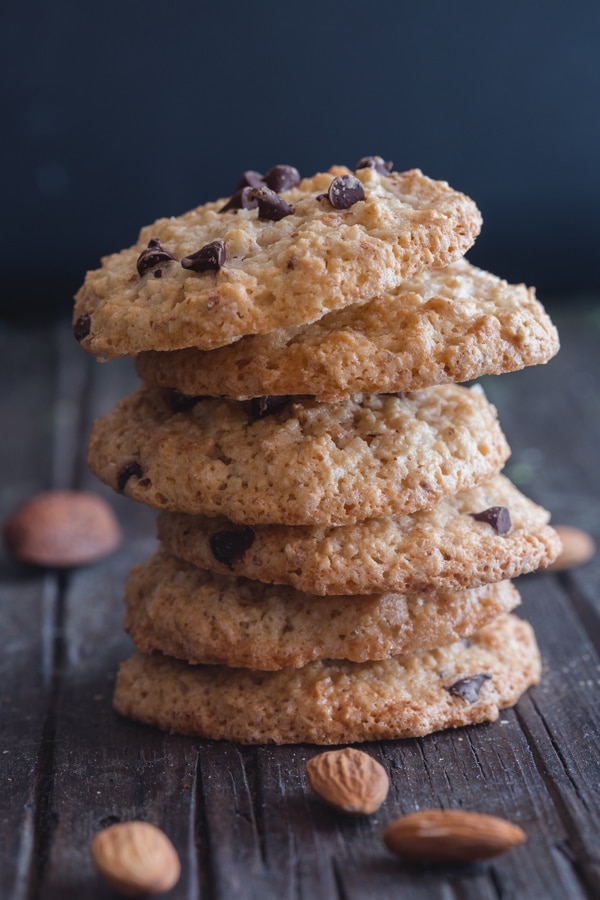 6 amaretti cookies stacked on one another on a blue board with almonds scattered