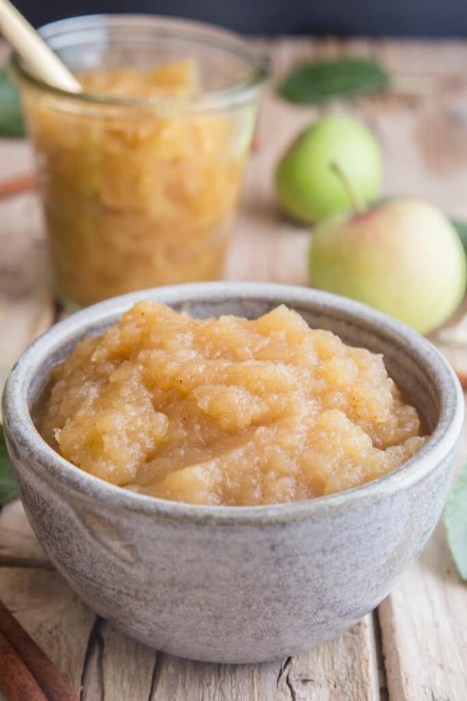 Homemade applesauce in a blue bowl and jar.