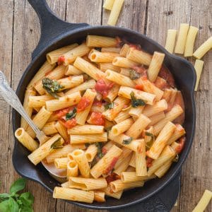 basil tomato sauce with pasta in an iron skillet
