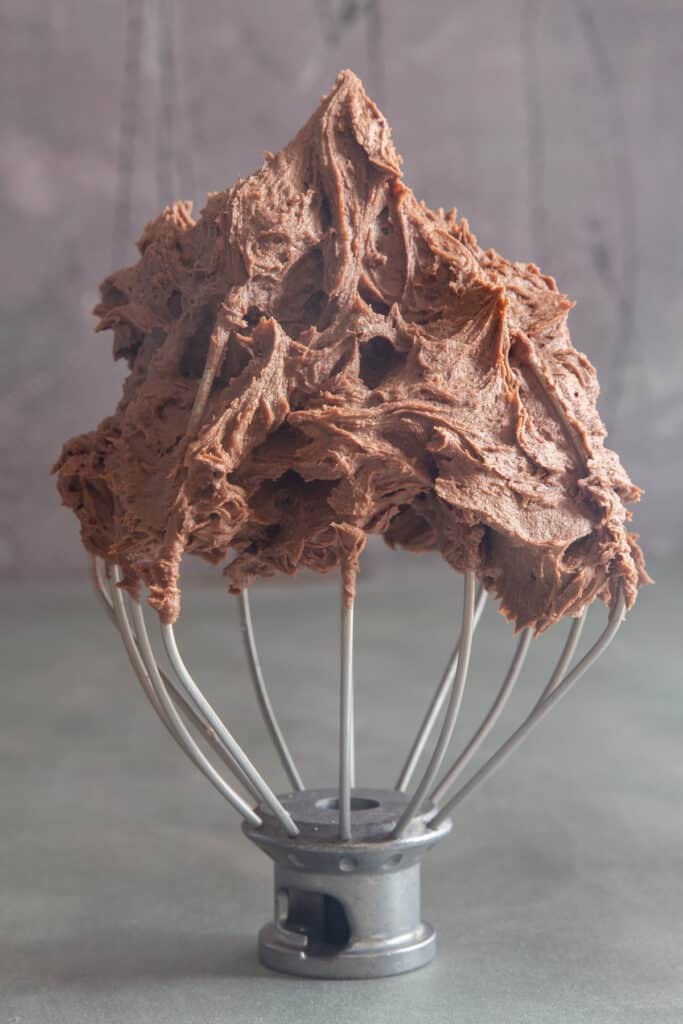 Chocolate butter frosting on a machine whisk.