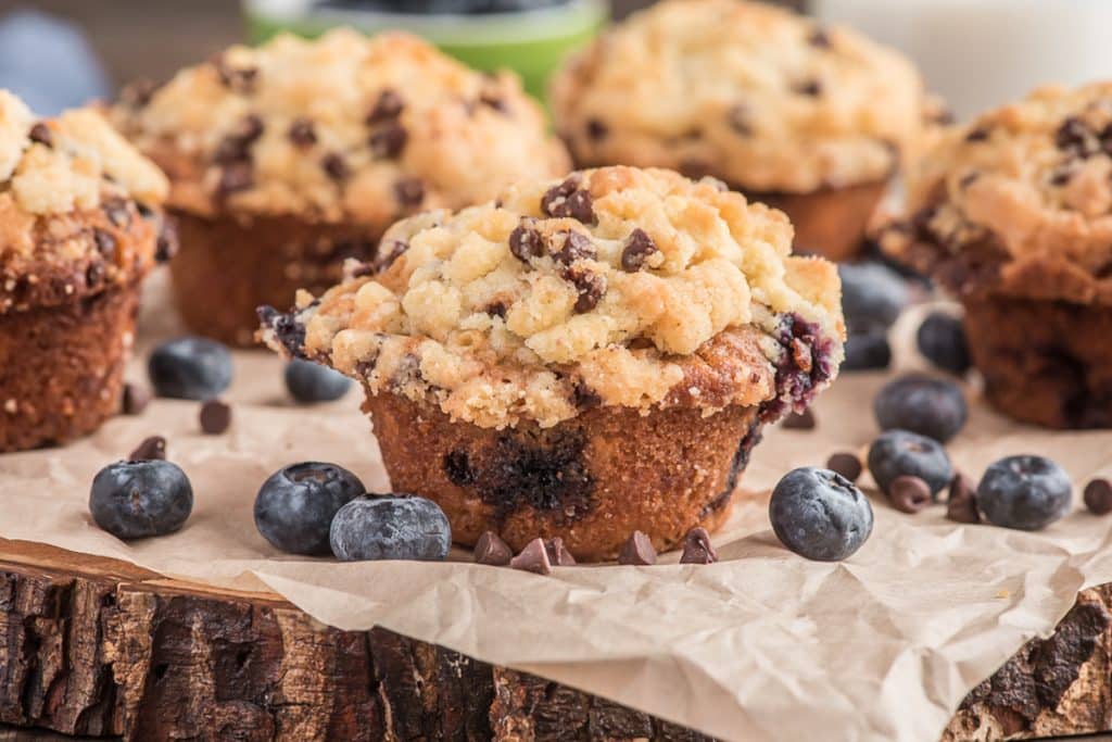 Muffins on brown paper with blueberries.