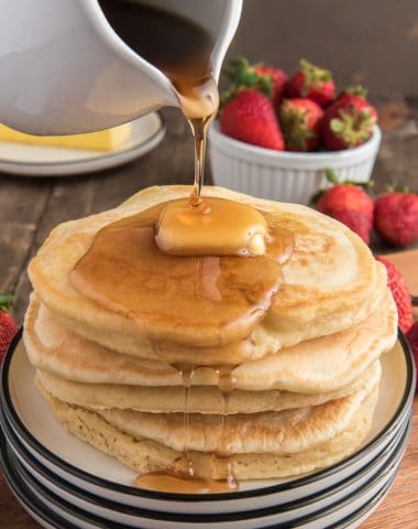 5 pancakes stacked with some butter and syrup.