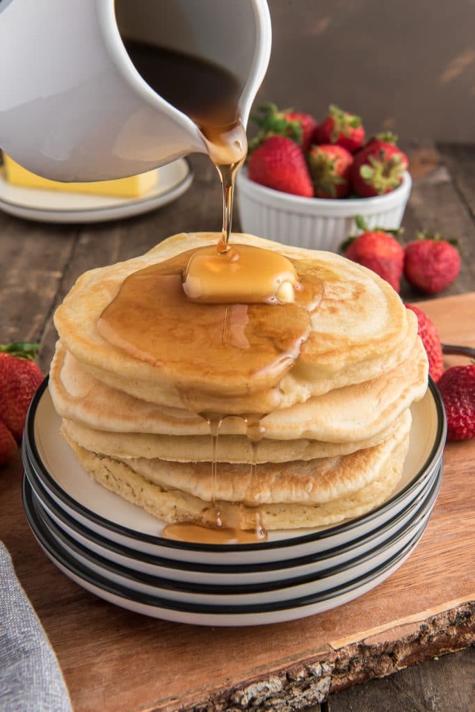 Pancakes stacked and pouring on the syrup.