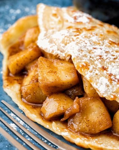Apple pie stuffed crepes on a blue plate.
