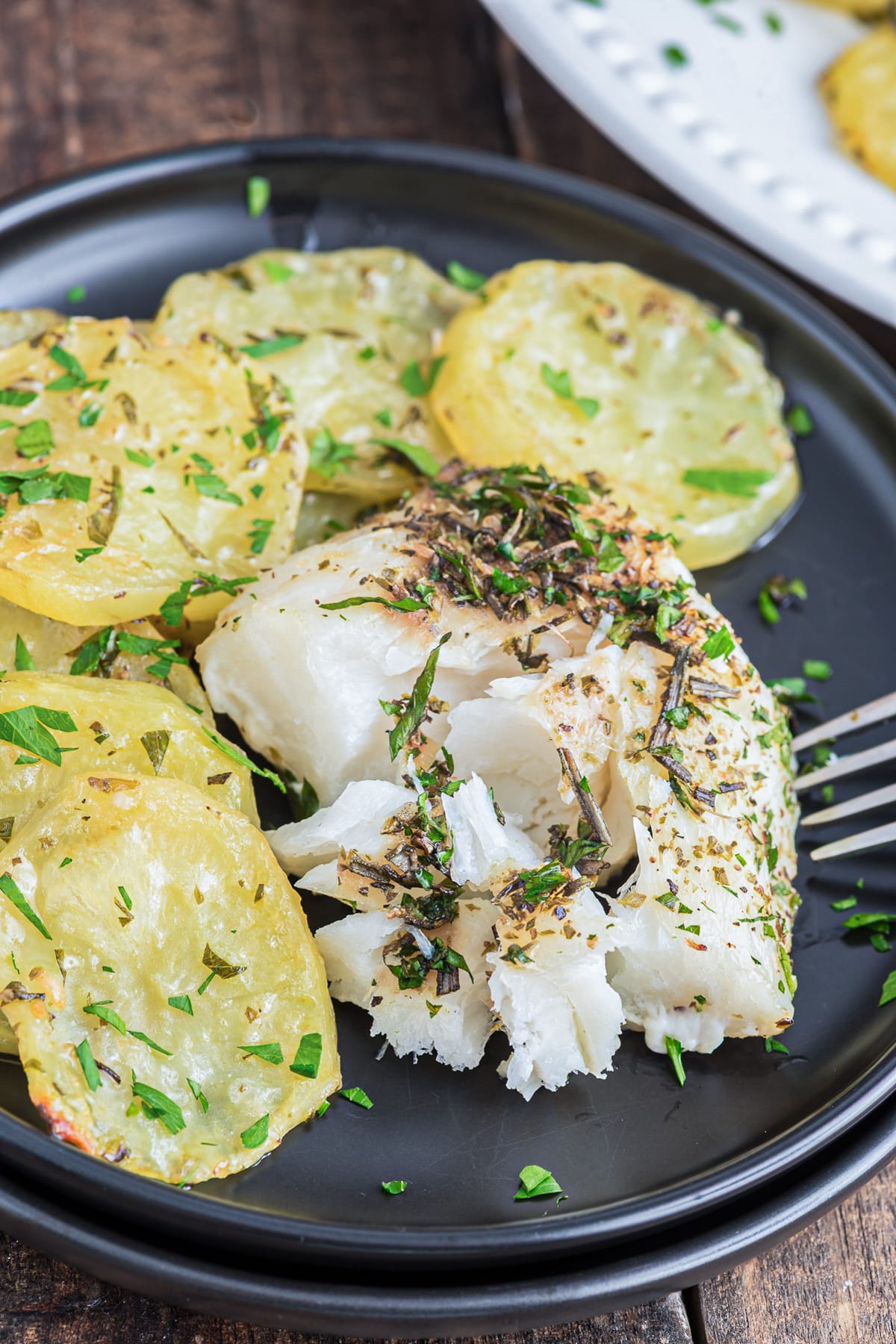 Baked fish and chips in a black plate.