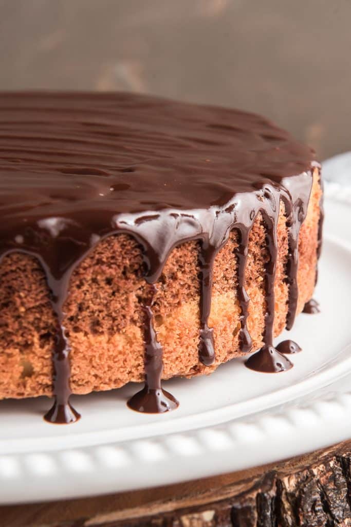 Chocolate glazed cake on a white plate.