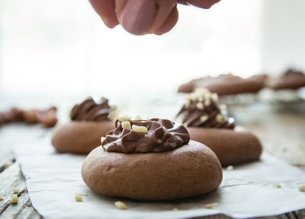 sprinkling chopped nuts on a baked nutellotti cookie