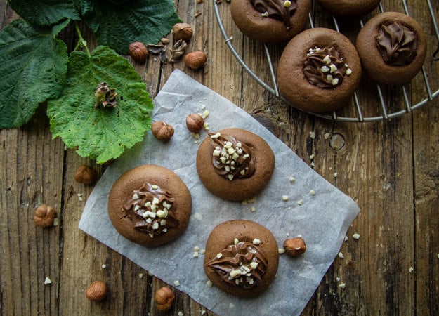 nutellotti cookies on a wooden board with chopped nuts on top
