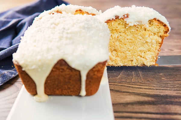 coconut pound cake on a white board with a slice cut