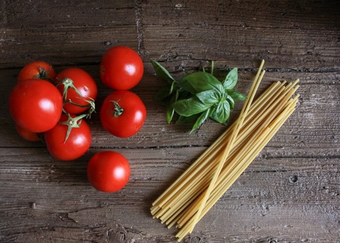 tomatoes, basil and pasta on a board.