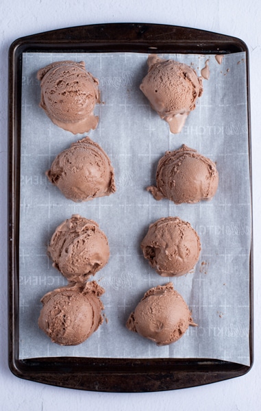 Ice cream scoops on a parchment paper cookie sheet.