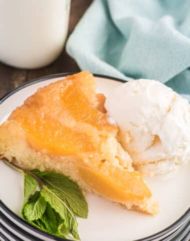 A slice of peach upside cake on a plate with ice cream.