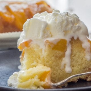 a slice of peach upside down cake on a plate with a scoop of ice cream on top.