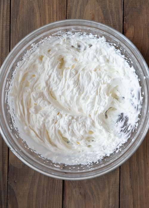 Whipped cream beaten in a glass bowl.
