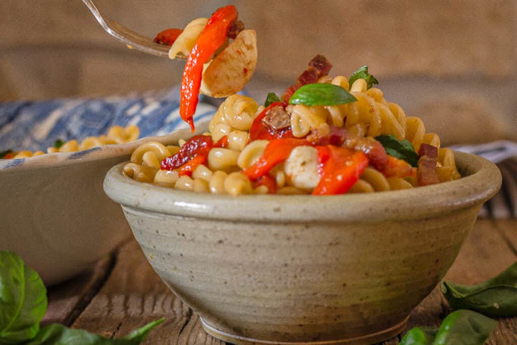Pepper pasta in a grey bowl and some on a fork.