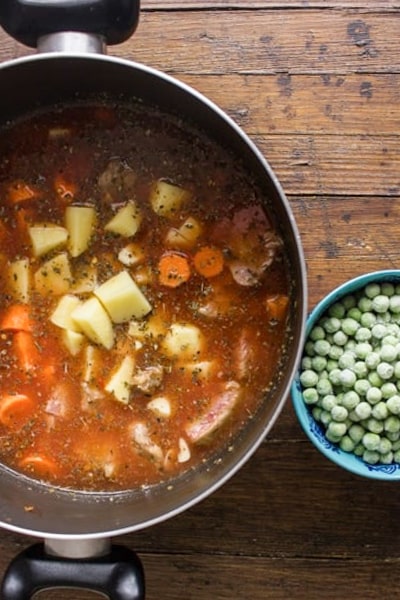 The ingredients in the pot and peas in a bowl.