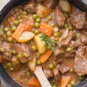 Beef stew in a pot with a wooden spoon.
