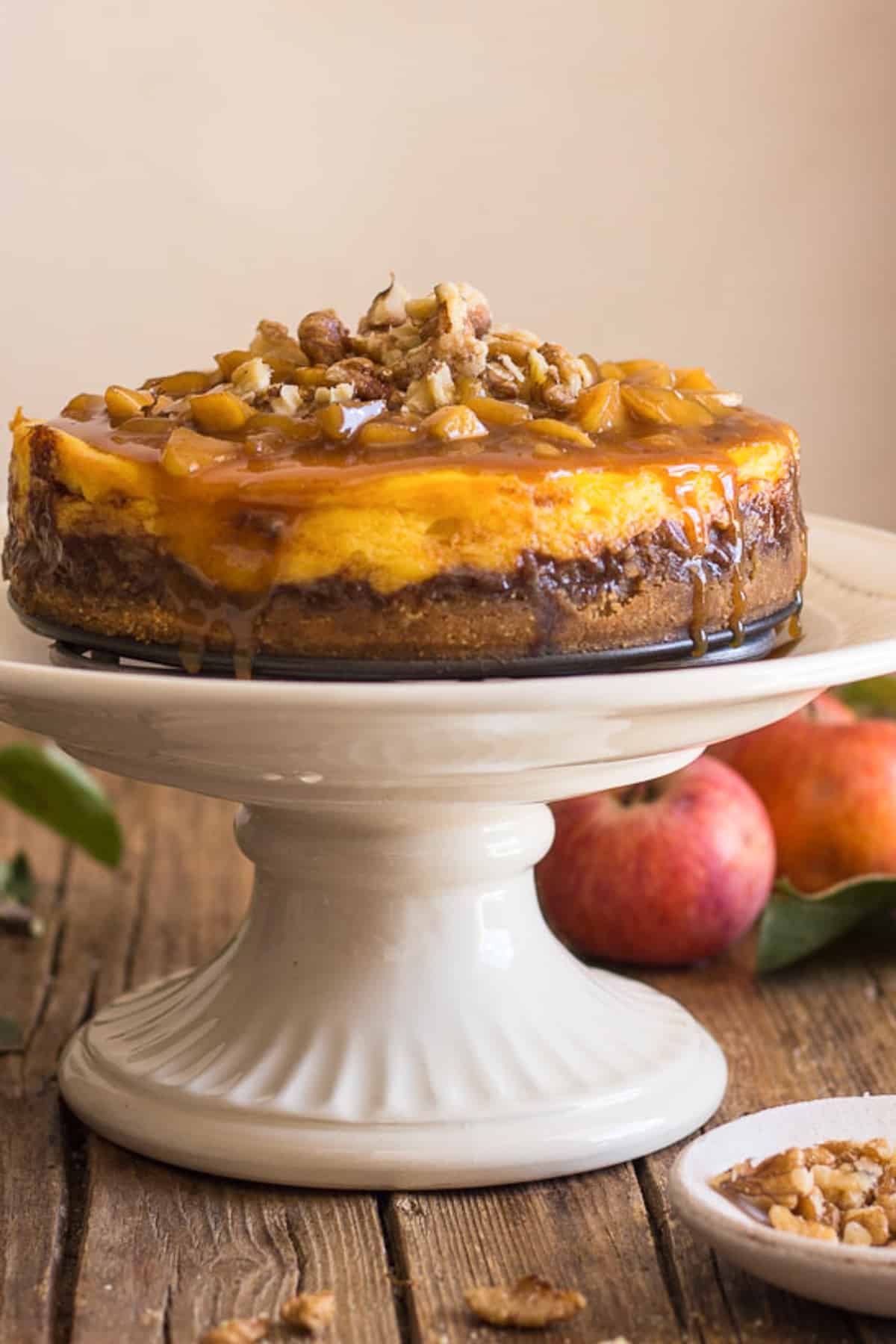 Apple cheesecake on a white cake stand.