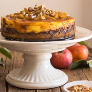 Apple cheesecake on a white cake stand.