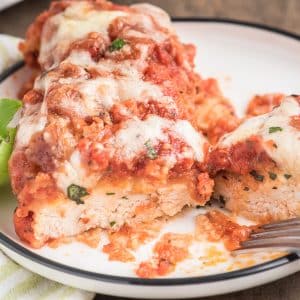 Chicken parm on a white plate with a fork.