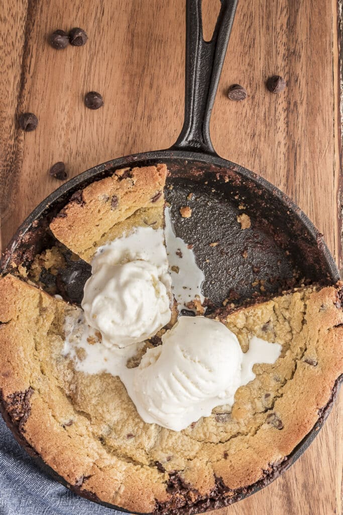 Cookie skillet in a black pan with two scoops of vanilla ice cream.