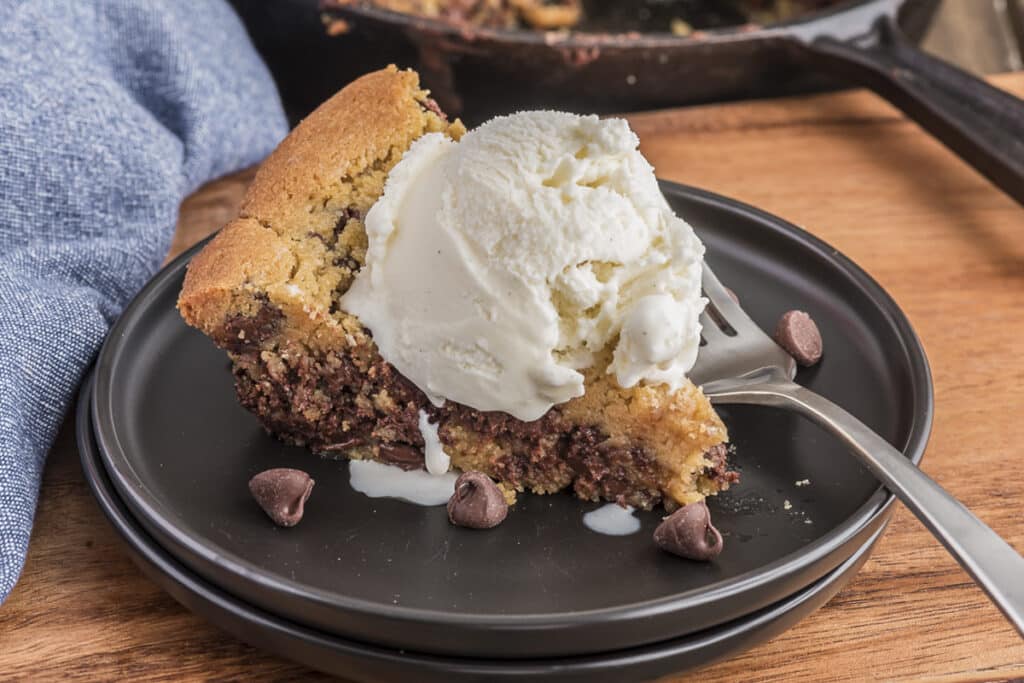 A slice of cookie pie on a black plate.