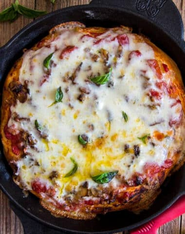 Pizza in a skillet with a pizza knife.