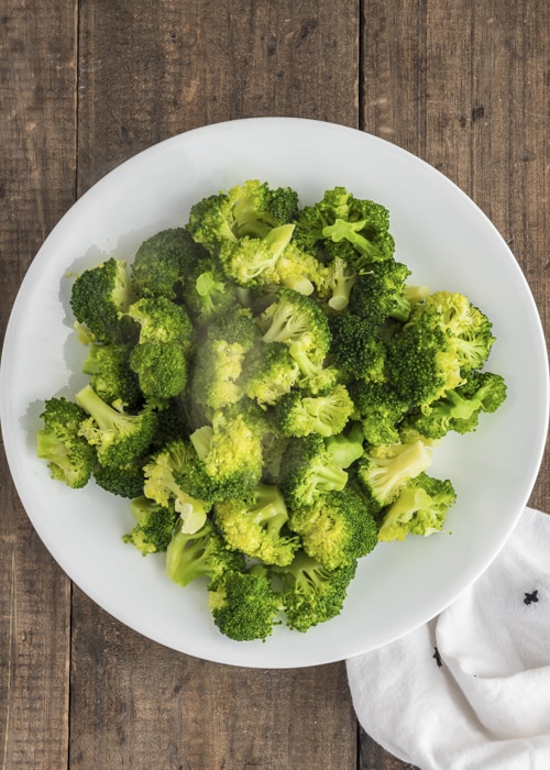 The cooked broccoli in a white bowl.