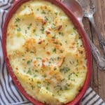 Cheesy mashed potato casserole in a red dish.