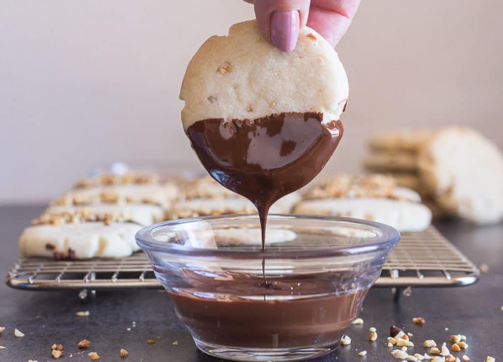 Dipping a cookie in melted chocolate.