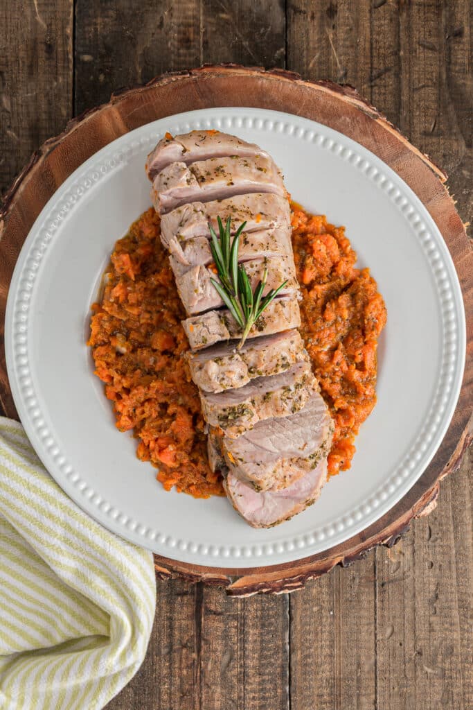 The sliced pork roast on a white plate with carrots.