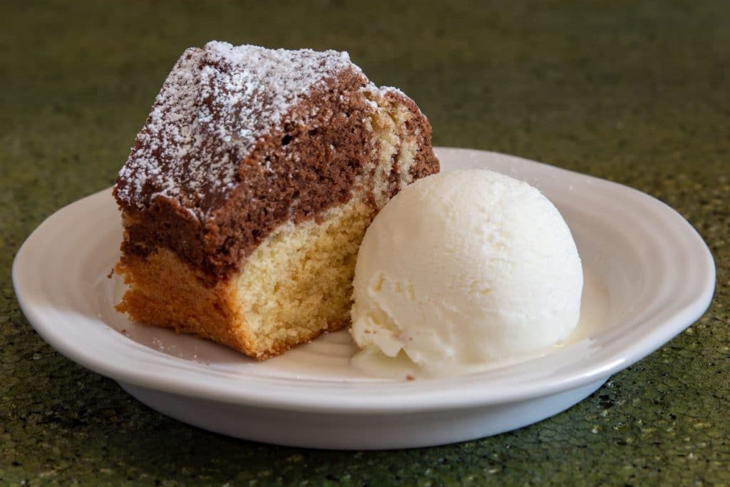 A slice of cake on a white plate with a scoop of ice cream.