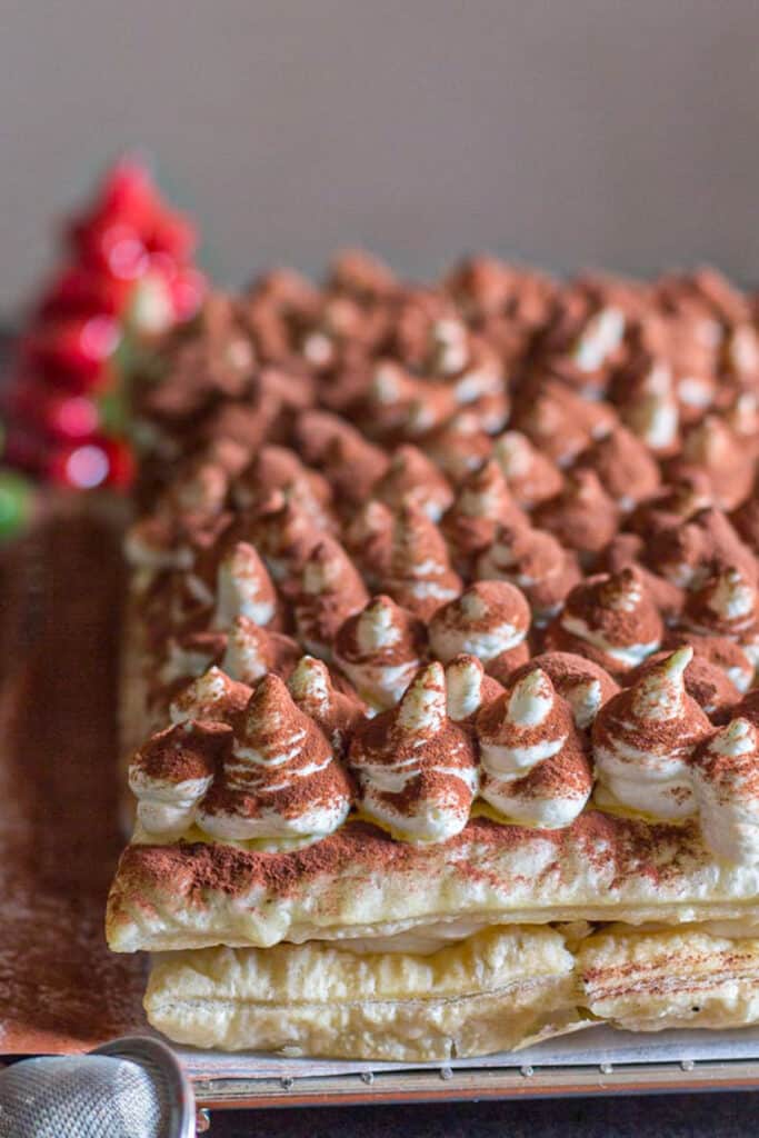 Tiramisu puff pastry on a black plate.