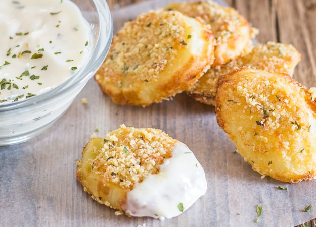 a parmesan potato rounds dipped in mayo with 3 in the background