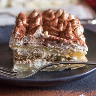 up close puff pastry tiramisu on a black plate.