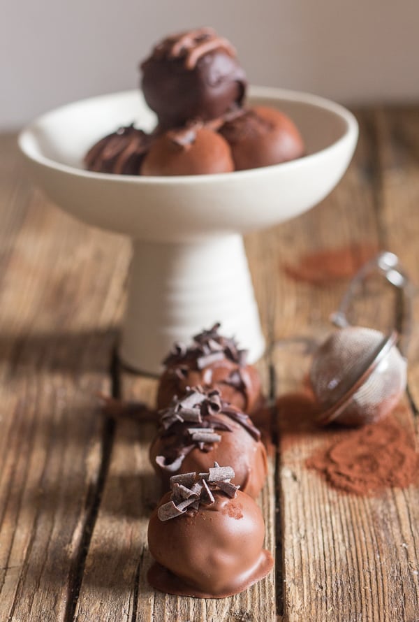 3 tiramisu truffles in front of a white bowl with truffles.