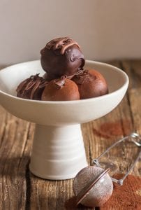 4 tiramisu truffles on a white bowl and pedestal