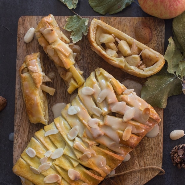 apple cinnamon strudel on a wooden board with 3 pieces cut