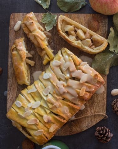 apple cinnamon strudel on a wooden board with 3 pieces cut