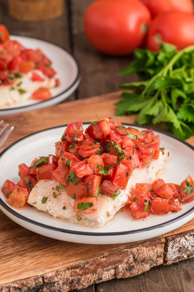 Baked fish marinara on a white plate.