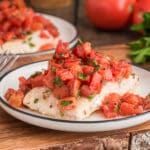 Baked fish marinara on a white plate.