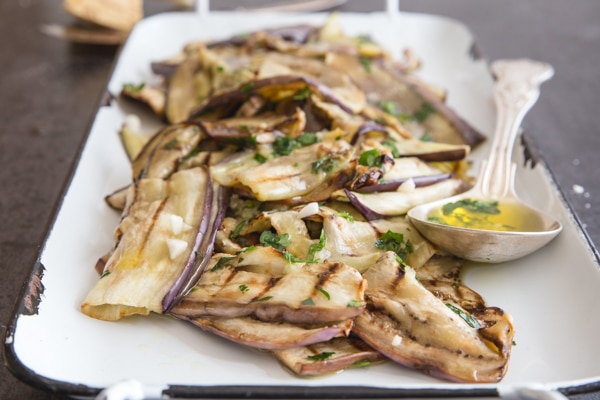 grilled eggplant on a white pan with a silver spoon