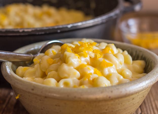 homemade macaroni and cheese in a bowl with shredded cheese on top