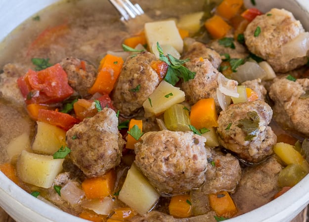 upclose photo of Italian meatball soup in a white bowl