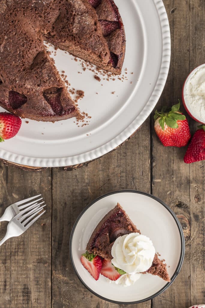 Strawberry chocolate cake slice on a white plate with a slice on a small white plate.