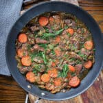 Beef and wine sauce in a black pan.