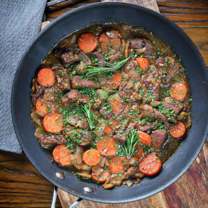 Beef and wine sauce in a black pan.