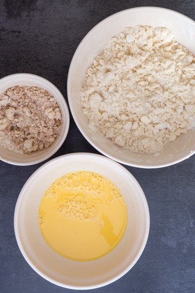 The whisked dried ingredients in a bowl, the egg, sugar and vanilla beaten in a white bowl and the streusel in a bowl